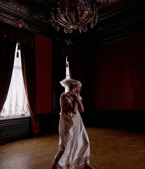 Woman in a calm, flowing movement pose in a dark room.